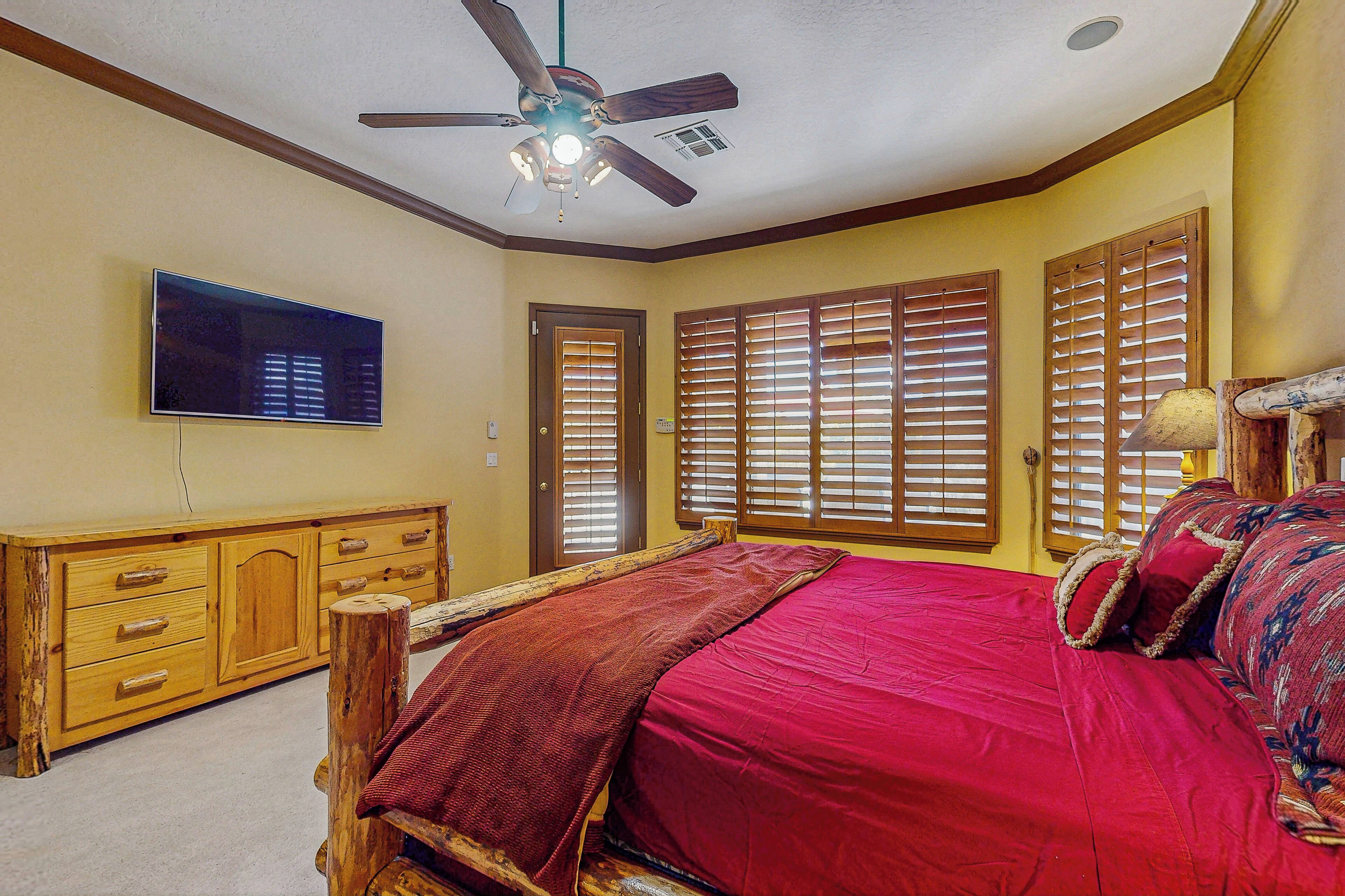 Un dormitorio con cama, cómoda de madera y ventilador de techo.