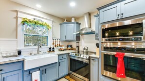 Una cucina moderna con mobili azzurri, elettrodomestici in acciaio inossidabile e una finestra vista alberi.