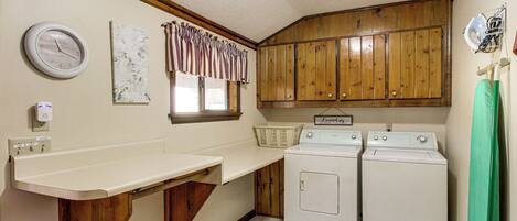 A laundry room with wooden cabinets, a washing machine, and a sink.