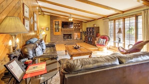 A cozy living room with a fireplace, leather sofas, and a large window. - 3 Mi to Ruby Falls: 'the Downer House' w/ Yard (Chattanooga)