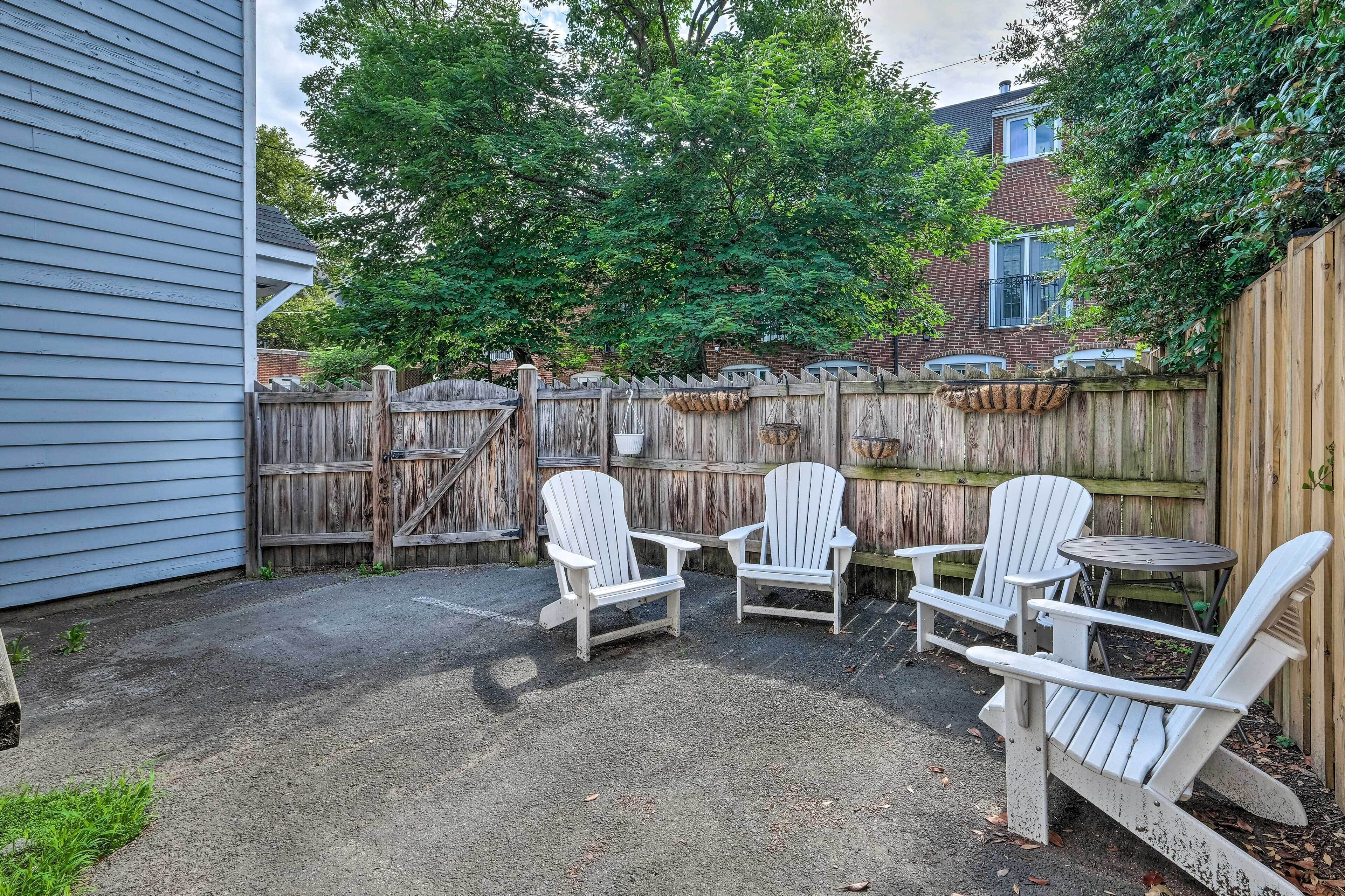 Un jardin avec une clôture en bois, deux fauteuils Adirondack et une petite table ronde.