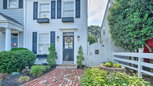 A two-story house with a brick pathway leading to the front door, which has a wreath. - Old Town Walkable Paradise w/ Private Patio! (Alexandria)