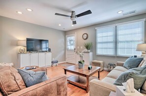 A living room with a television, sofa, coffee table, and a ceiling fan. - Old Town Walkable Paradise w/ Private Patio! (Alexandria)