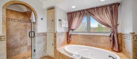 Un baño con cabina de ducha, bañera y ventana con cortinas.