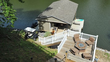 A lakeside deck with outdoor furniture, a covered area, and a dock extending into the water.