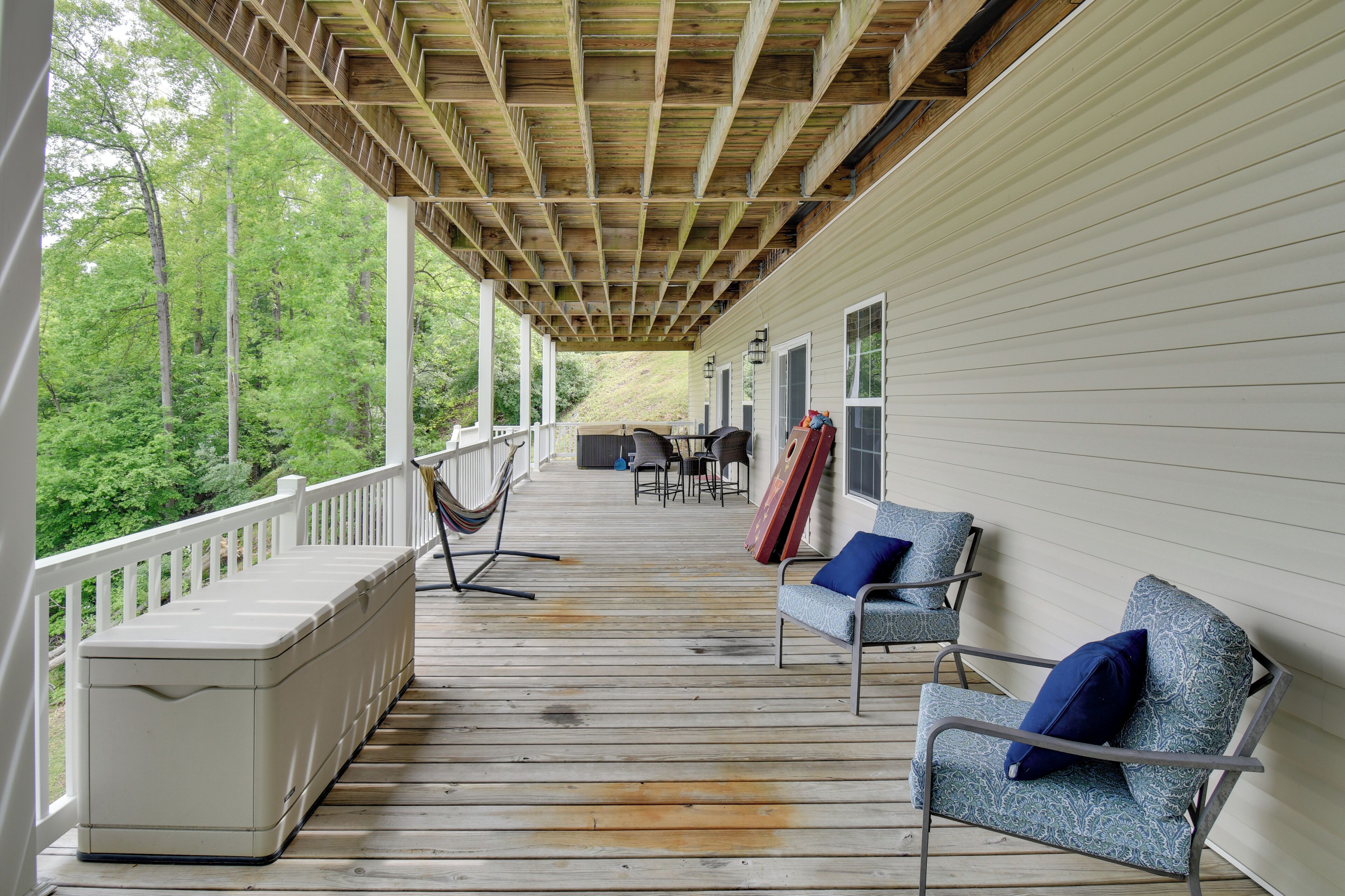 A covered porch with a wooden ceiling, white railings, and a seating area with a table and chairs.