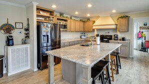 A modern kitchen with a large island, stainless steel appliances, wooden cabinets, and a variety of kitchen tools and decorations. - Private Hot Tub! Getaway on Smith Mountain Lake (Goodview)