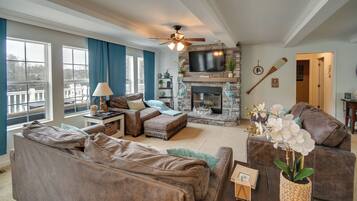 A spacious living room with a fireplace, comfortable seating, and a television.