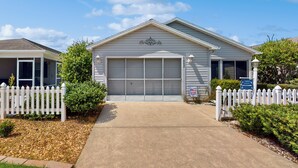 A single-story house with a garage, white picket fence, and a clear driveway. - Dog-friendly Home w/ Golf Cart, AC, Wifi (The Villages)