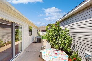 Eine Terrasse mit Tisch, Stuhl und einem kleinen Gartenbereich mit Pflanzen und Blumen.