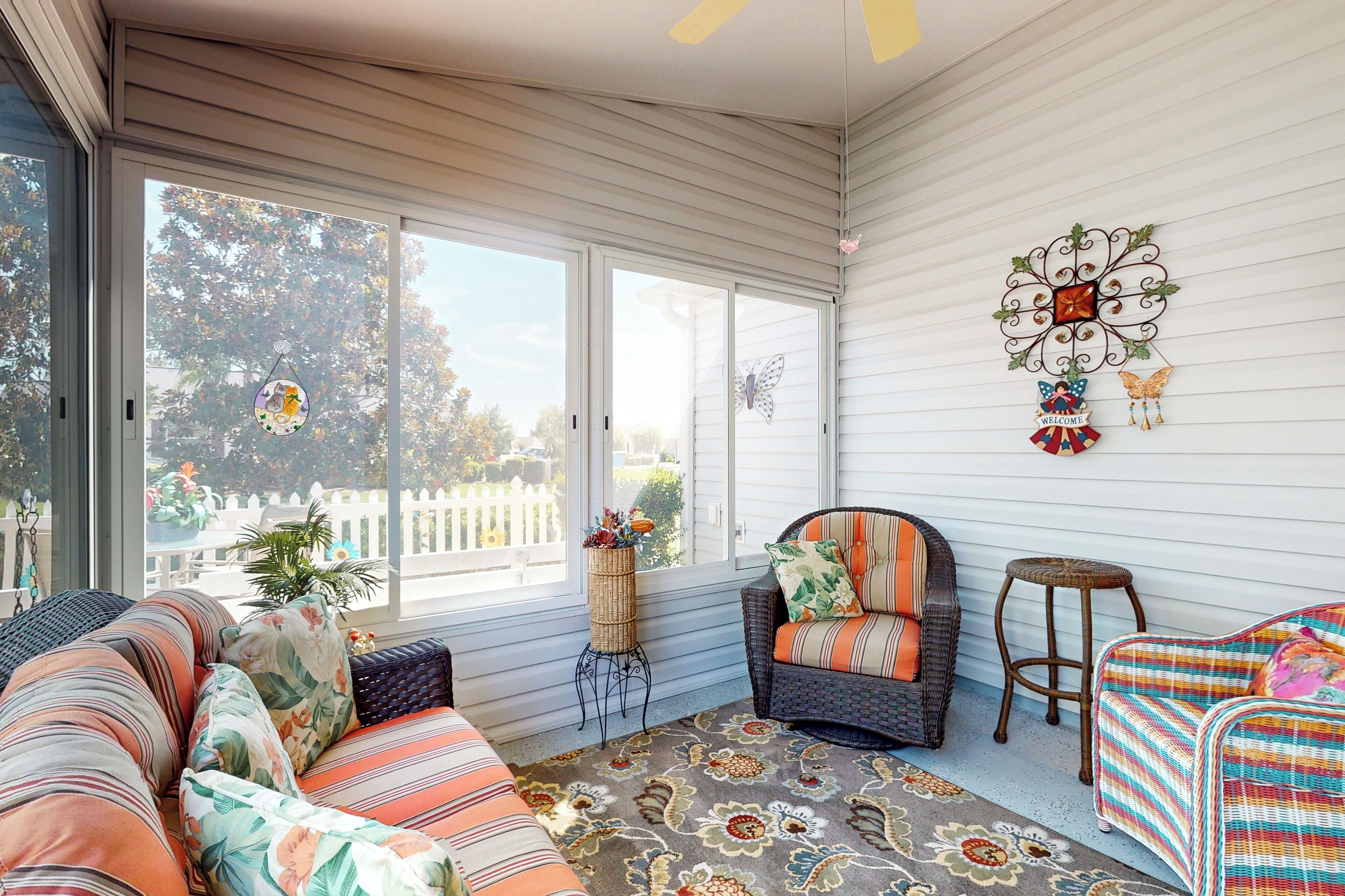 A sunlit room with a sofa, a chair, a small stool, and a decorative wall piece.
