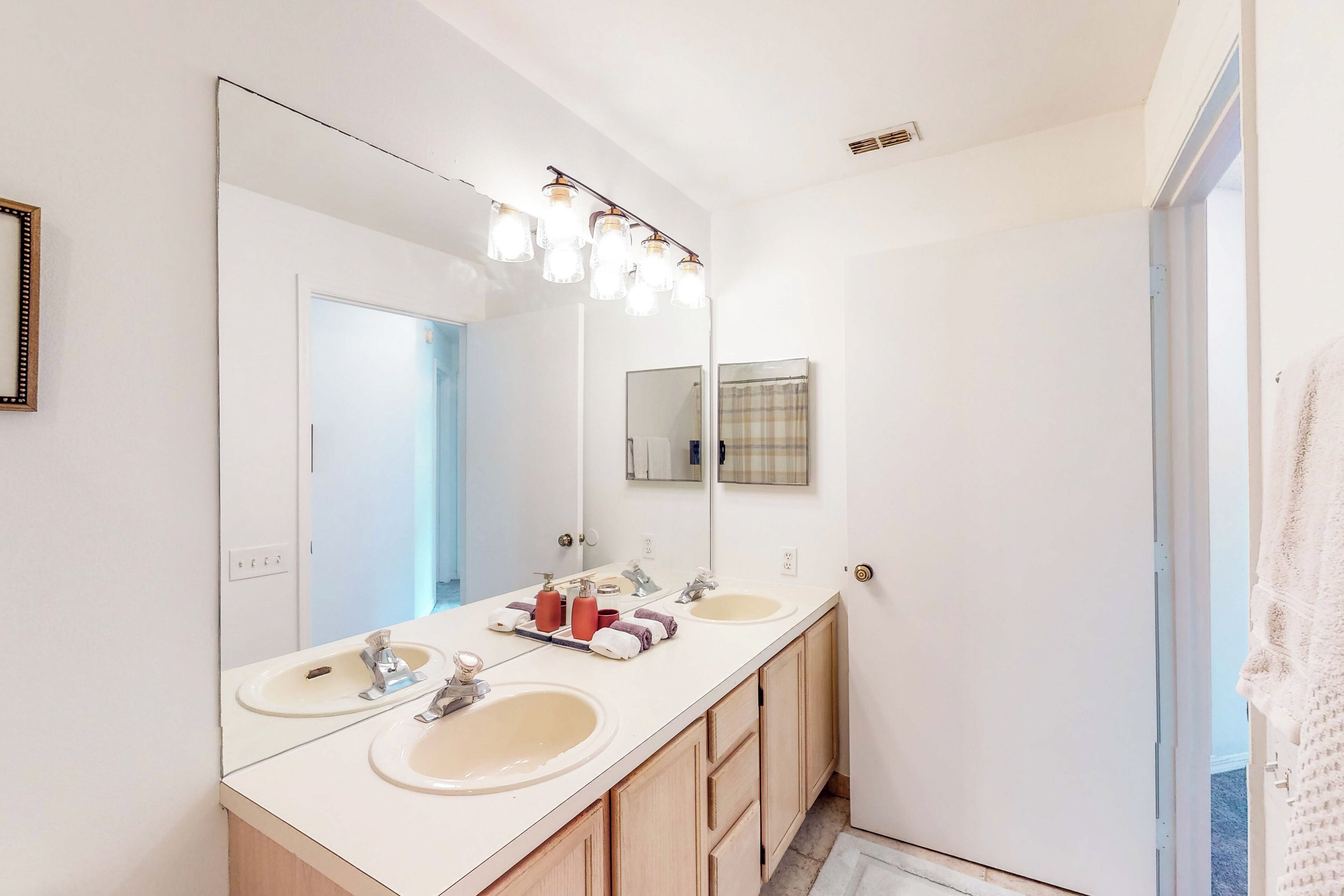 A bathroom with two sinks, a large mirror, and a light fixture above the mirror.
