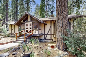 A cabin with a wooden staircase, a balcony, and a stone fireplace. - 2BR House w/ Private Hot Tub, Free Wifi (Big Bear City)