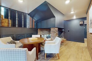 A cozy living area with a stone fireplace, a round wooden table, and patterned chairs. - Buckthorn Beauty: Golf, Hike & More (Show Low)