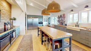 A modern kitchen with a central island, pendant lighting, and a brick accent wall. - Buckthorn Beauty: Golf, Hike & More (Show Low)