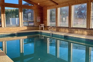 Eine Holzhütte mit Schwimmbecken, großen Fenstern und einem Schild, das vor rutschigen Böden warnt.