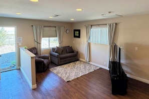 A living room with a brown sofa, a small table, a rug, and a TV stand. - Near Parks, Shops & Eats! Bullhead City Casita (Bullhead City)