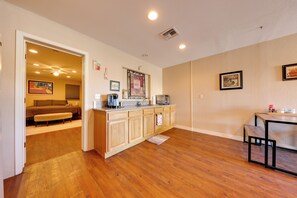 A kitchen with wooden cabinets, a countertop, and a dining area with a table and bench. - Near Parks, Shops & Eats! Bullhead City Casita (Bullhead City)