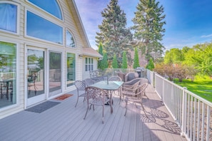 A covered deck with outdoor furniture, large windows, and a view of trees and a house. - Waterfront Alexandria Gem: Family & Group Friendly (Alexandria)