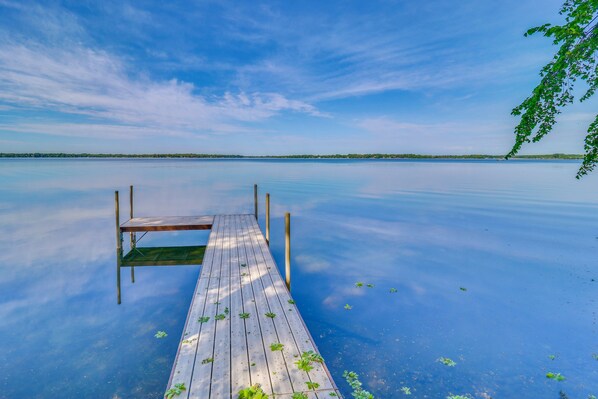 Une jetée en bois s’étendant sur une étendue d’eau calme, sous un ciel dégagé.
