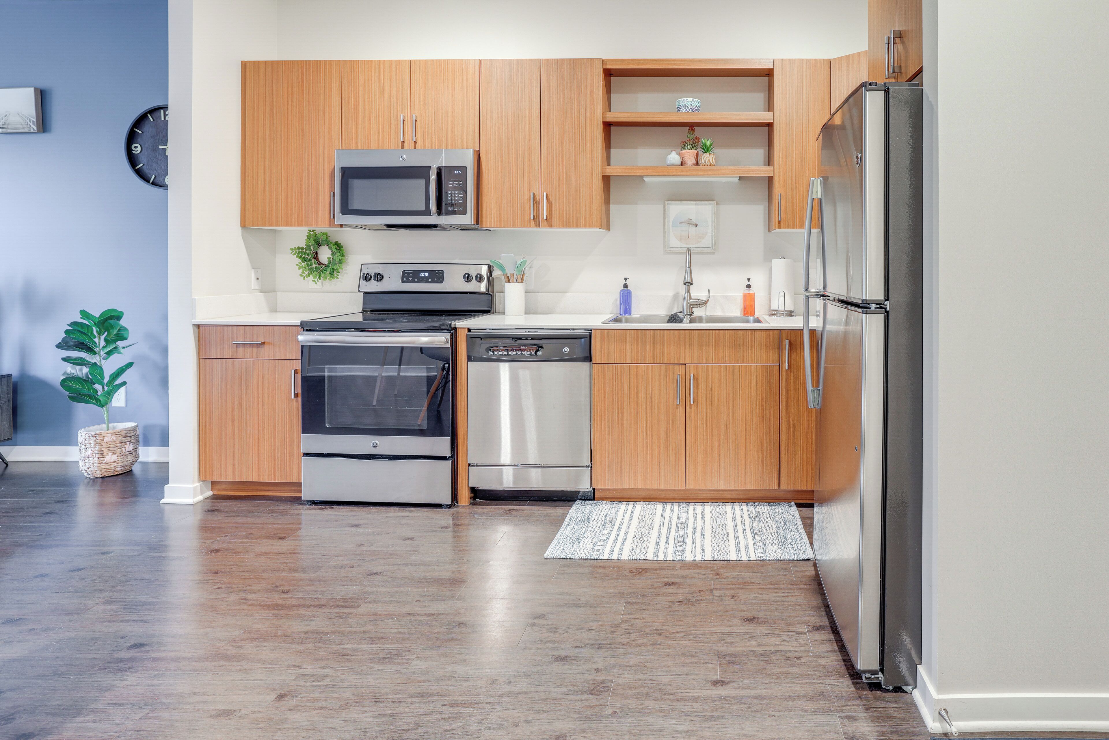 A modern kitchen with wooden cabinets, stainless steel appliances, and a built-in microwave.