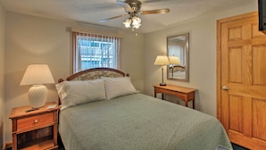 A bedroom with a bed, nightstands, a ceiling fan, a window with blinds, a wooden door, and a mirror. - Apt. Walking Distance to OOB Pier & Saco Bay! (Old Orchard Beach)