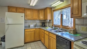 A kitchen with wooden cabinets, a refrigerator, a dishwasher, a stove, and a window with curtains. - Apt. Walking Distance to OOB Pier & Saco Bay! (Old Orchard Beach)