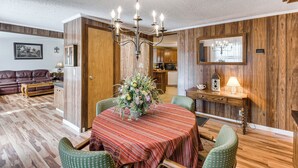 A dining area with a round table, chairs, a chandelier, and wooden walls. - Countryside Haven w/ Spacious Yard in Tamassee! (Tamassee)