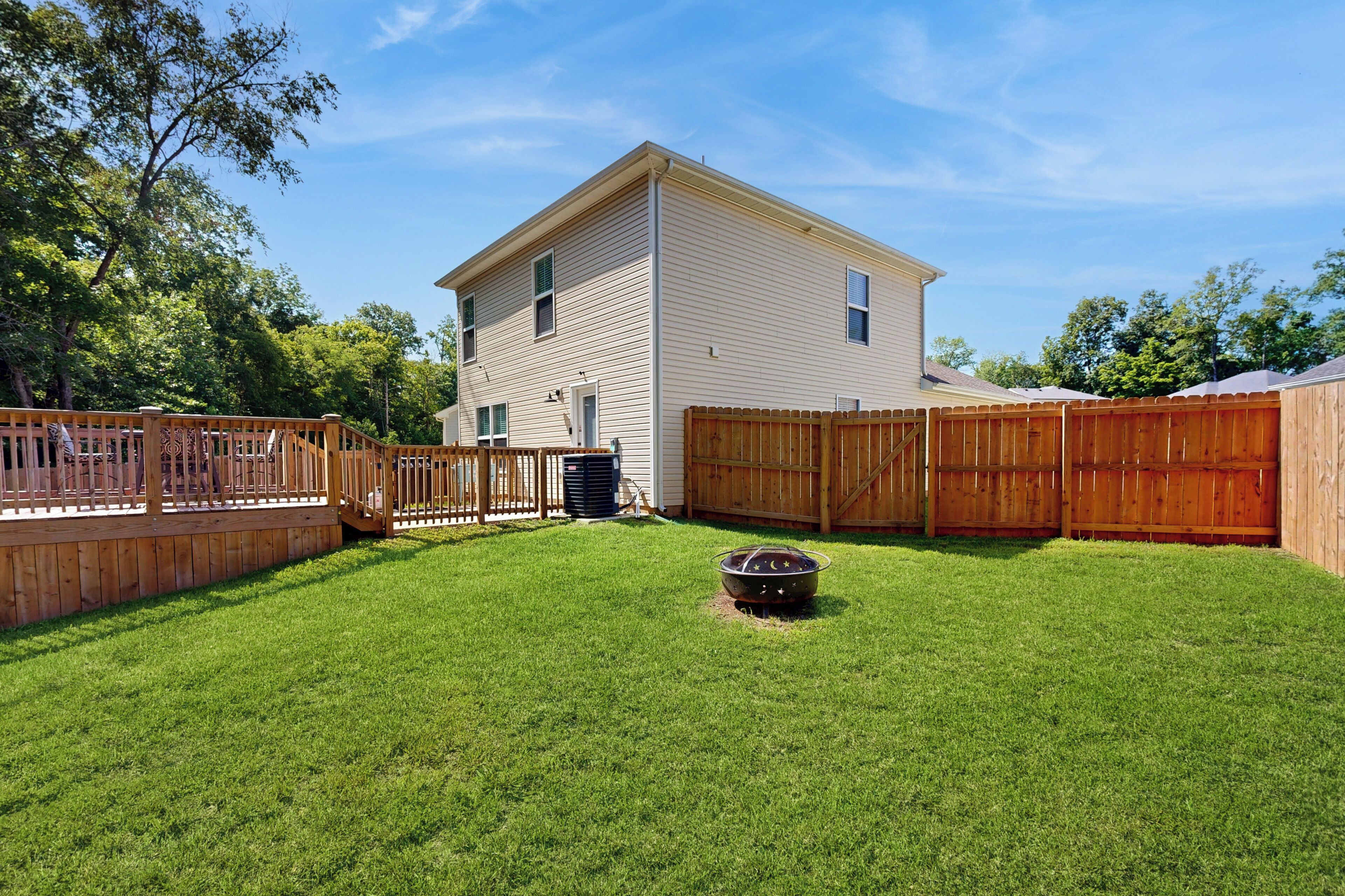 A two-story house with a fenced backyard, a hot tub, and a wooden deck.