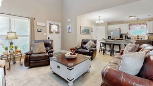 A spacious living room with leather sofas, a coffee table, and a kitchen in the background. - Gateway to Fort Campbell! Home w/ Furnished Deck (Clarksville)