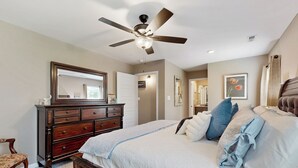 A bedroom with a bed, dresser, ceiling fan, and a large mirror. - Gateway to Fort Campbell! Home w/ Furnished Deck (Clarksville)