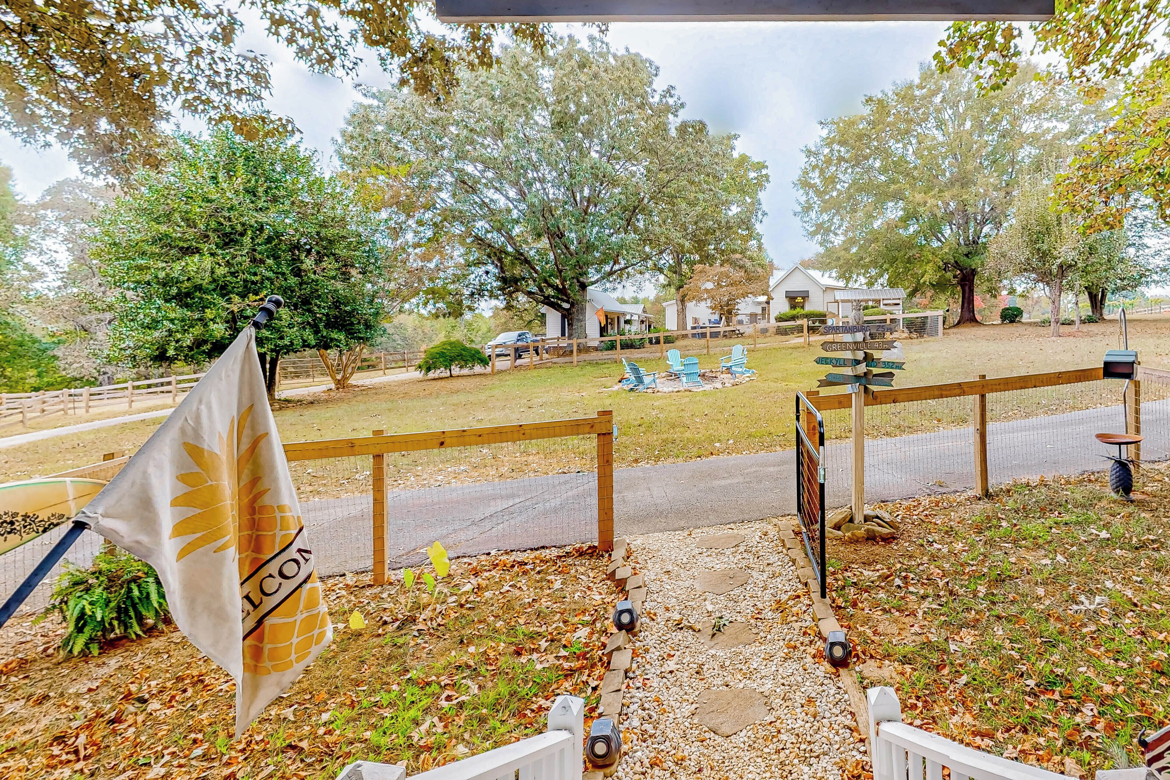 A fenced outdoor area with a flag, a wooden structure, and a pathway leading to a building.