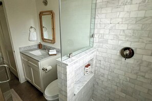 A bathroom with a marble vanity, a glass shower enclosure, and a toilet. - Off-grid & Elegant Farmhouse Near Somerville Lake (Brenham)
