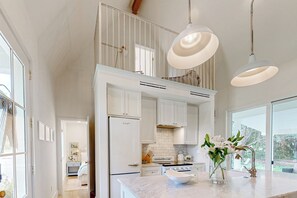 Una cucina moderna con mobili bianchi, una grande isola e luci a sospensione.