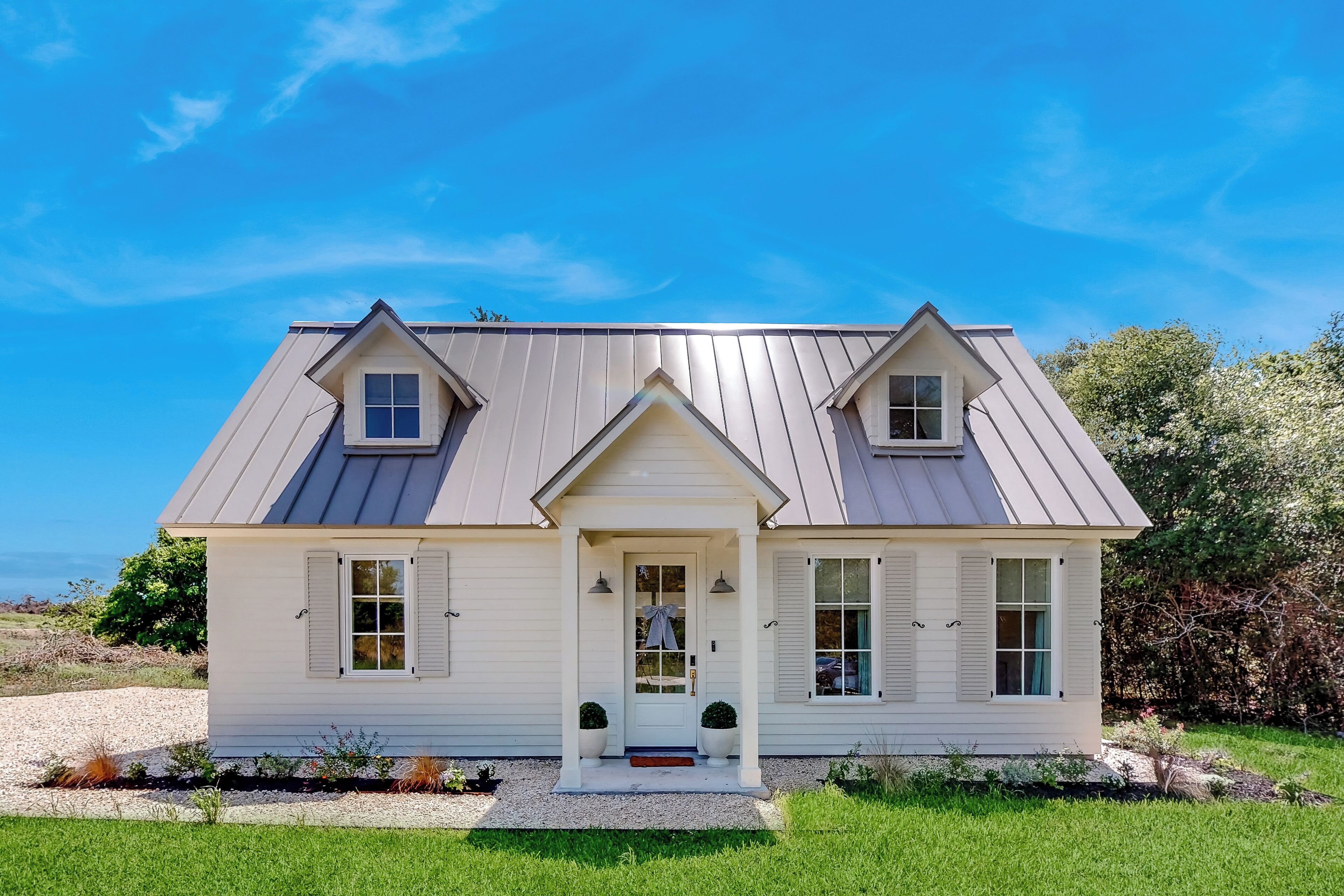 A two-story house with a symmetrical facade, a front porch, and a gravel driveway.