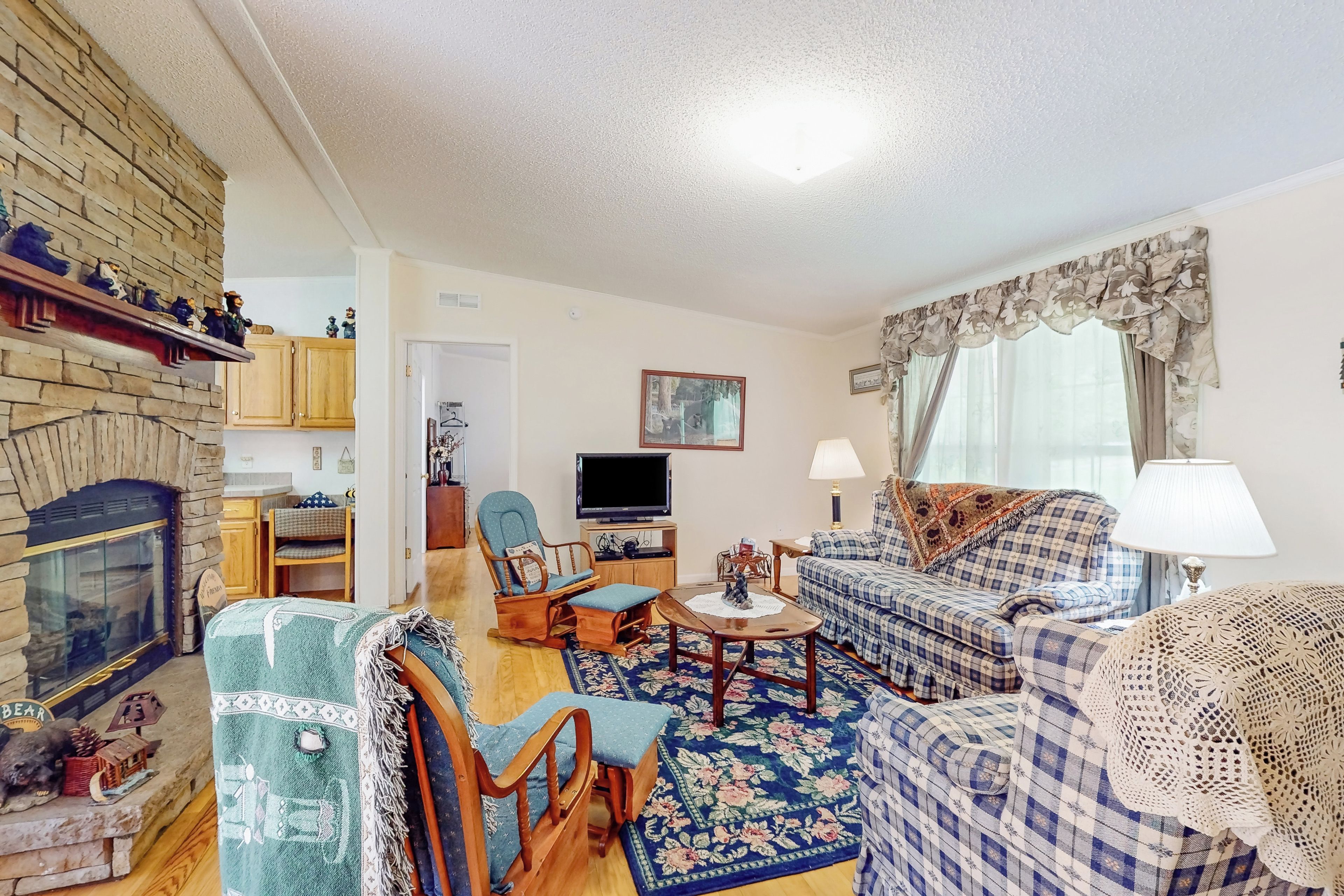 A cozy living room with a stone fireplace, wooden furniture, and a television.