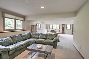 A spacious living room with a green leather sectional sofa, a coffee table, and a dining area with a wooden table and chairs. - Plymouth House: Walk to Beach & Medicine Lake! (Plymouth)