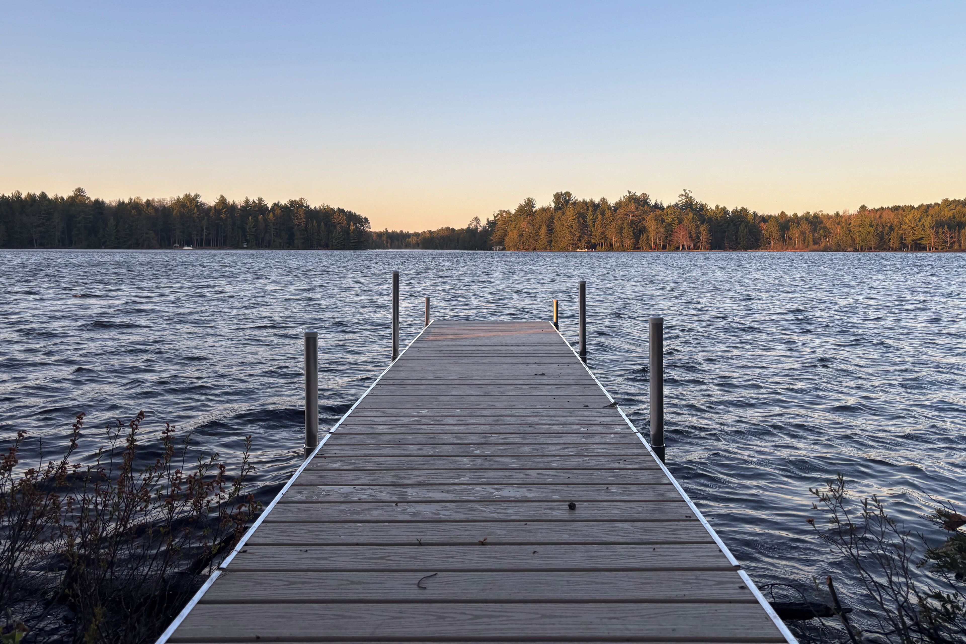 A wooden pier extending into calm water, surrounded by trees.