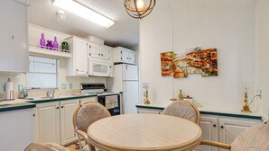 A kitchen with white cabinets, a microwave, a refrigerator, and a dining table with chairs. - Snowbird Escape w/ Pools! 6 Mi to Dtwn Sarasota (Sarasota)
