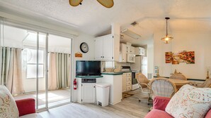 A modern living room with a sofa, television, and a kitchen area with cabinets and a dining table. - Snowbird Escape w/ Pools! 6 Mi to Dtwn Sarasota (Sarasota)