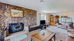 Ein gemütliches Wohnzimmer mit Steinwand, Kamin, Ledersofa und Fernseher.