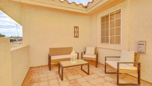 Eine Terrasse mit zwei Korbschaukeln, einem Holztisch und einem großen Fenster.