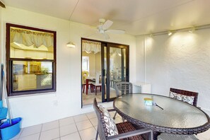 A dining area with a round glass table, wicker chairs, and a ceiling fan. - 1 Mi to Beach! Marco Island Family Getaway w/ Pool (Marco Island)