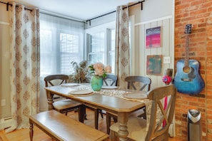 A dining area with a wooden table set for four, surrounded by chairs, a vase with flowers, and a guitar on the wall. - 2 Mi to Talcott Mtn Trails: Spacious Family Home (Bloomfield)