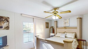 A bedroom with a large bed, a ceiling fan, a television, and a window with blinds. - Private Pool! Nat'l Forest Retreat on 1 Acre (Oakhurst)