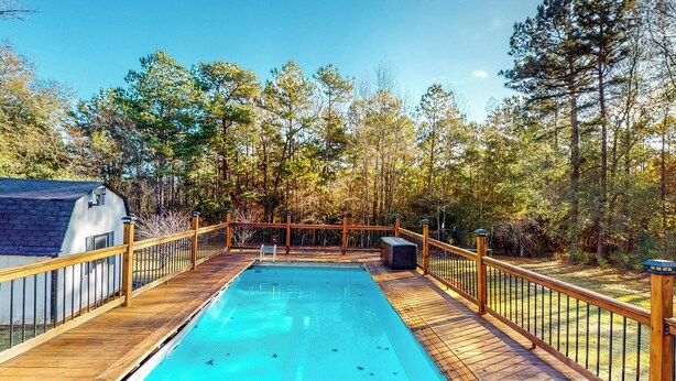 A wooden deck with a swimming pool, surrounded by trees and a house. - Private Pool! Nat'l Forest Retreat on 1 Acre (Oakhurst)