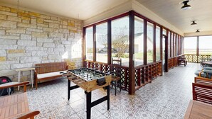 Un'ampia area interna con un tavolo da calcio, panche in legno e una parete in pietra.