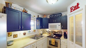 A kitchen with blue cabinets, a microwave, and a stove.