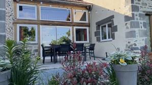 Una casa de piedra con un patio, una mesa con sillas y plantas en macetas.