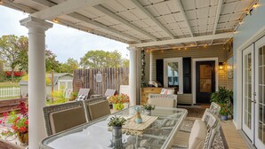 A covered patio with a glass table and wicker furniture, surrounded by potted plants and a wooden deck. - 2 Mi to Dtwn: Charming Sandusky Getaway w/ Hot Tub (Sandusky)